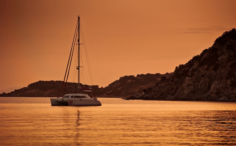 Familie auf Weltreise Katamaran Reise Sardinien Italien Katamaran in der Bucht alleinlage bei Sonnenuntergang